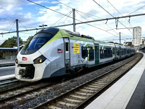 A white and green train traveling down train tracks